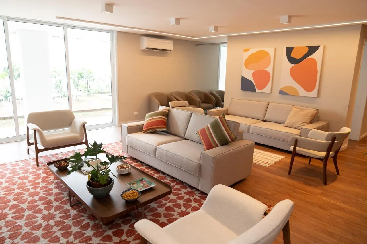 Sala de estar com sofás, poltronas, tapete estampado e quadros coloridos